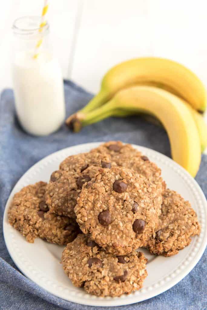peanut butter oatmeal cookies on white plate with bananas and milk in background