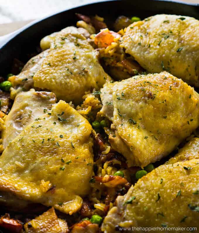 crispy chicken thighs over Spanish rice in cast iron skillet 