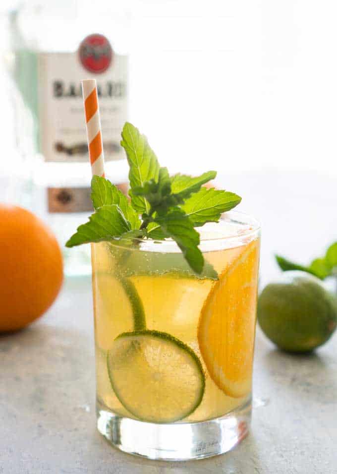 orange mojito with mint garnish and slices of lime and orange slices
