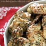 A serving dish full of Parmesan herb chicken wings next to a red and white napkin