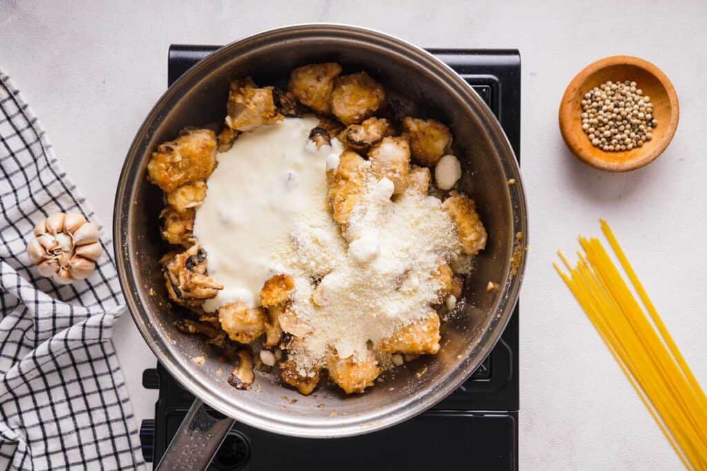 pan with chicken pieces, mushrooms, heavy cream, and parmesan cheese