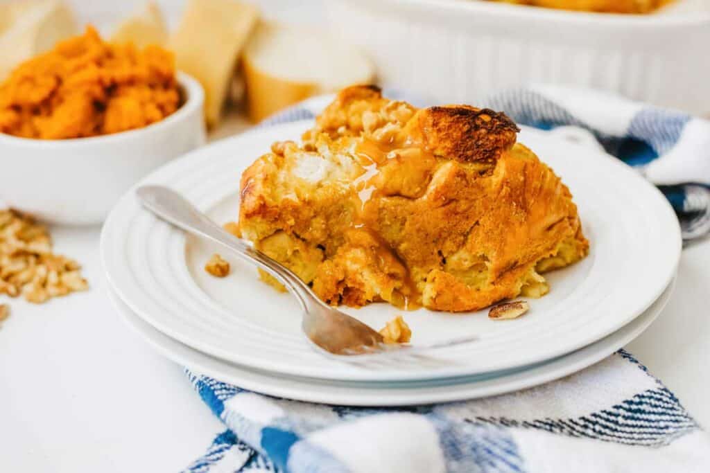 pumpkin bread pudding on white plate with fork and checked napkin