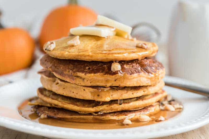 pumpkin pancakes with butter and syrup on white plate