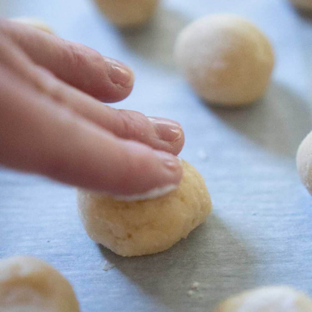 hand flattening ball of cookie dough