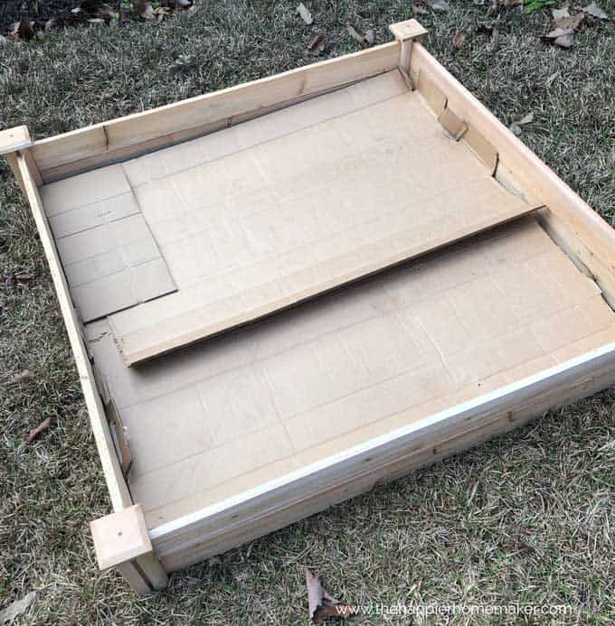 wooden raised garden bed with cardboard lining the bottom