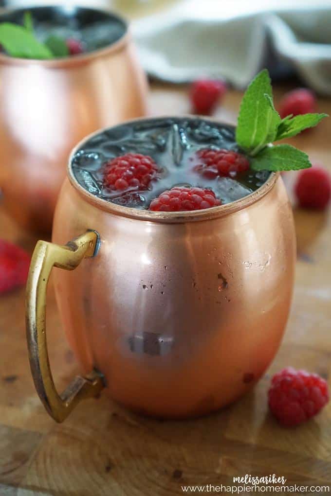 A close up of raspberry Moscow mule topped with raspberries and mint