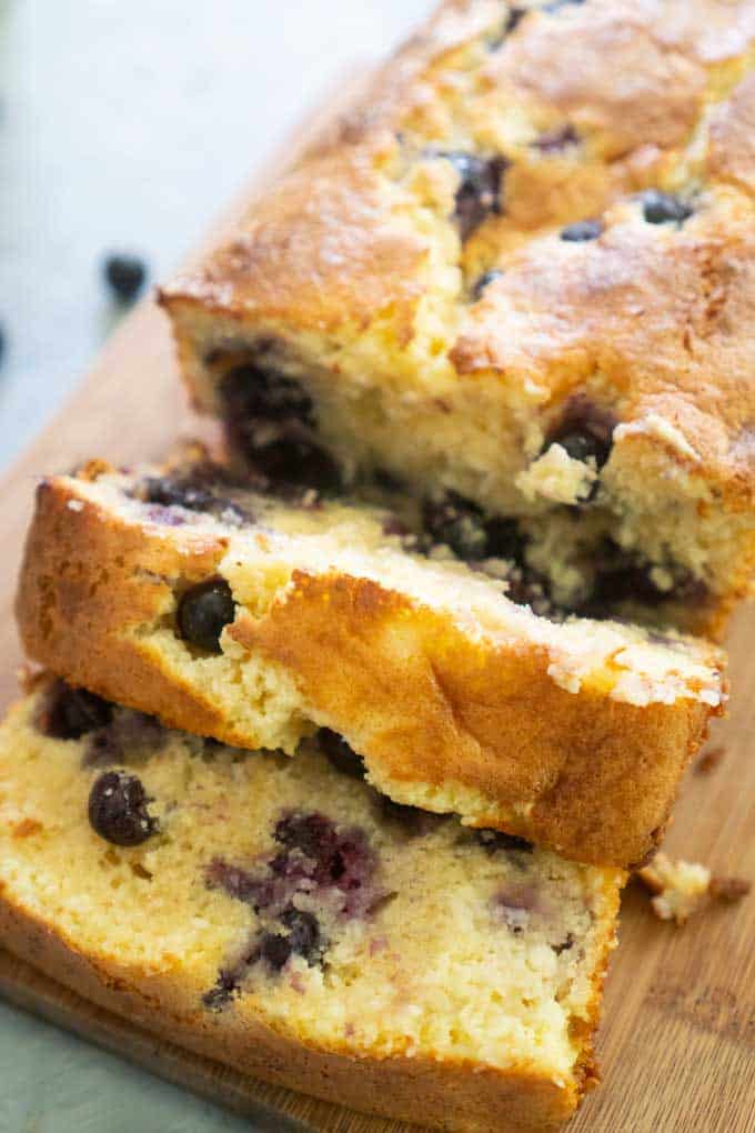 A close up of slices of blueberry cream cheese bread on wood cutting board