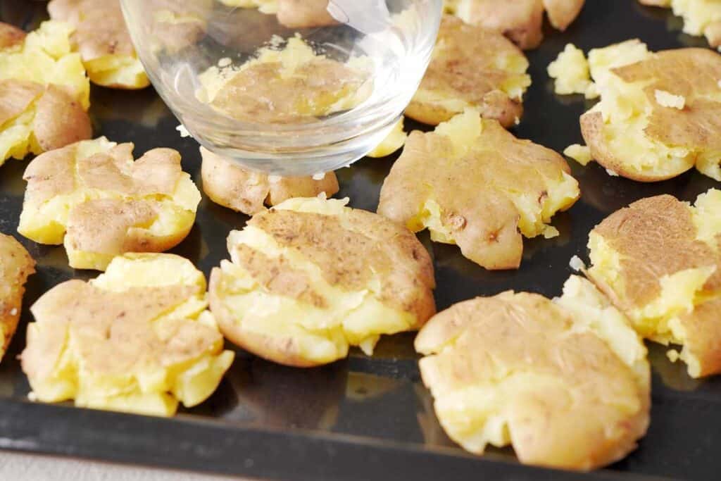 smashing potatoes with a glass on a baking sheet