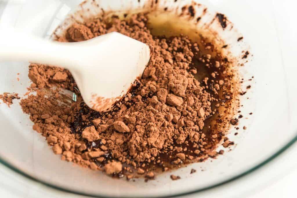 mixing cocoa powder into melted butter in glass bowl