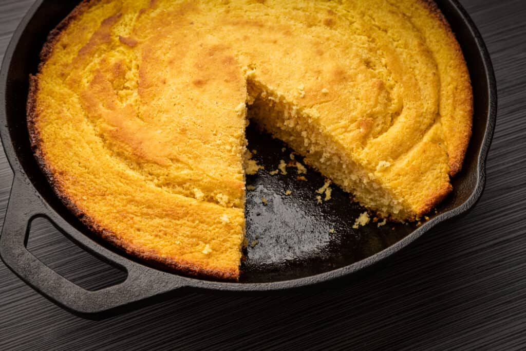 cast iron skillet with cornbread and one slice removed