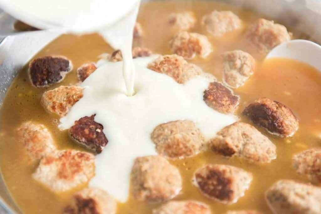 pouring sauce into pan of meatballs