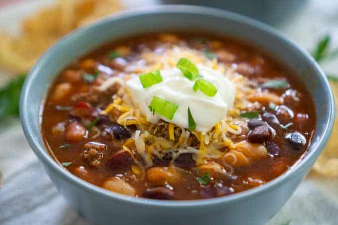 A close up of a bowl of Taco soup topped with cheese, sour cream and green onion