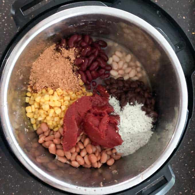 overhead view of corn, beans, tomato paste, and seasonings for taco soup with ground beef in instant pot