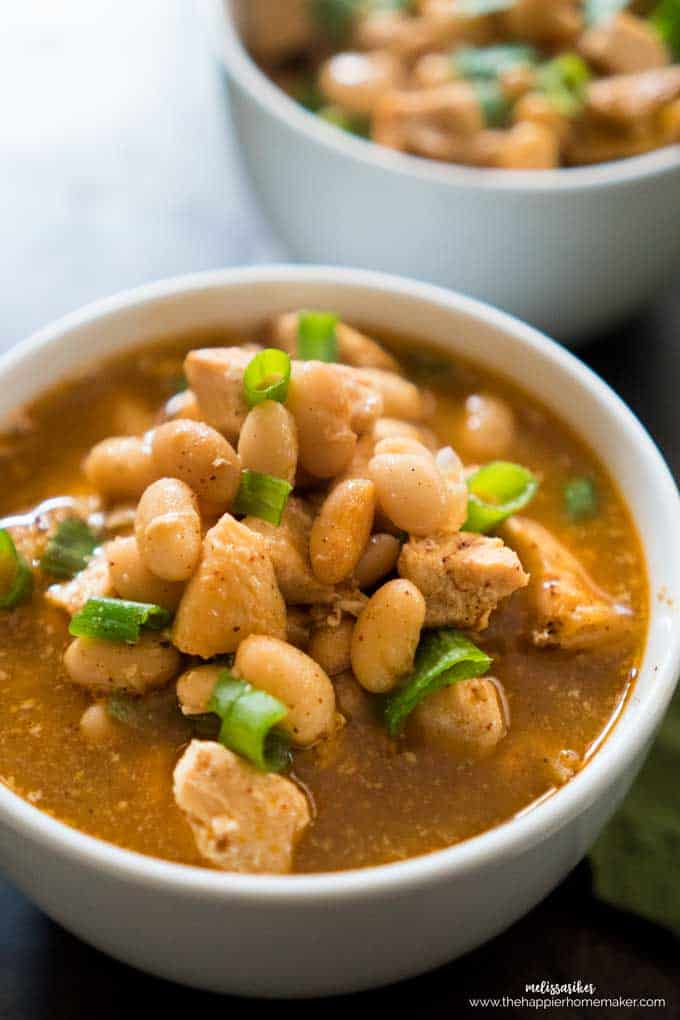 A close up of white chicken chili topped with green onion