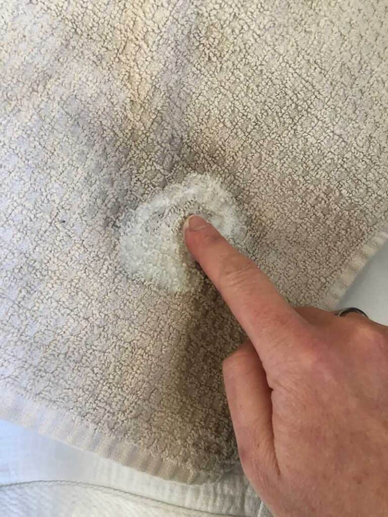 rubbing homemade stain remover in white towel with finger